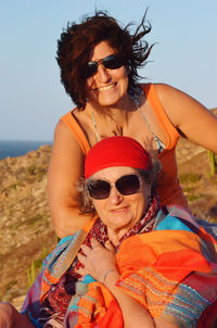 Portrait of   woman wearing sunglasses against sky with her smiling daughter 