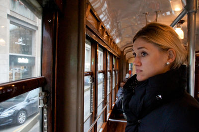 Thoughtful young woman looking through window while traveling in train