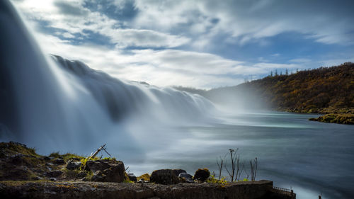 Scenic view of waterfall against sky