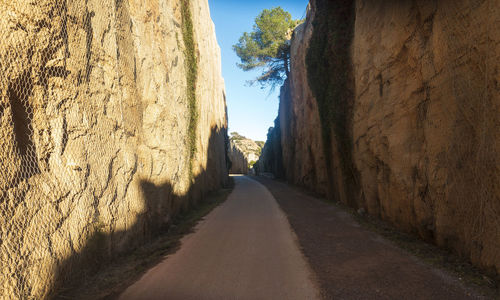 Empty road amidst rock formation against sky