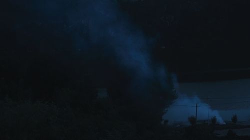 Illuminated trees on landscape against sky at night