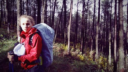 Portrait of girl standing on tree trunk in forest