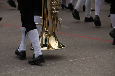 Low section of man holding musical equipment while walking on street