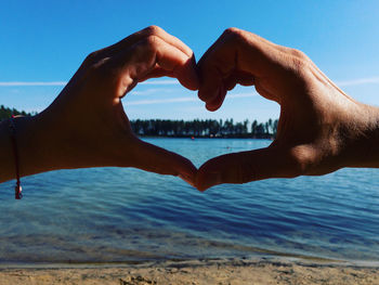 Midsection of heart shape on beach against sky