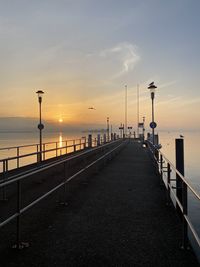 Street by sea against sky during sunset