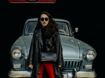 Portrait of young woman in car against black background