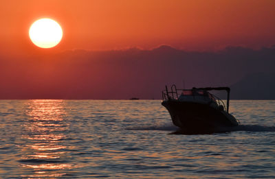 Boat sailing in sea against sky during sunset