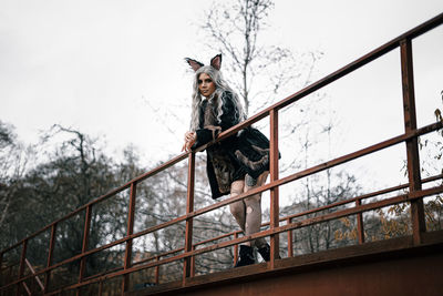 Low angle view of person standing by railing against sky