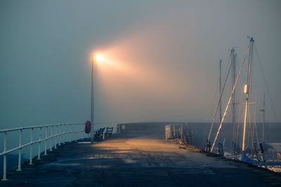 Diminishing perspective of pier against sky at sunset