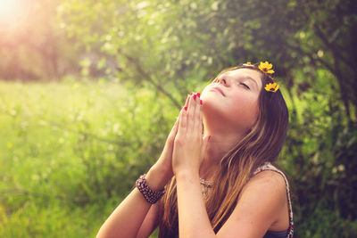 Hippie teenage girl praying against trees in forest
