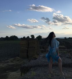 Woman with arms raised against sky