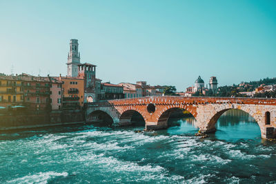 Sunny day in old city verona, italy. rough river embankment, arch bridge ponte pietra.