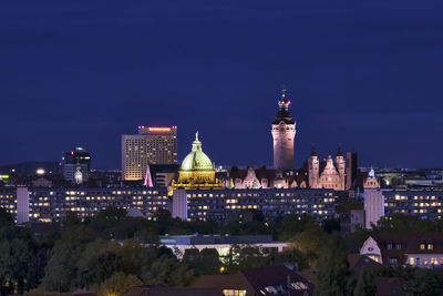 Illuminated buildings in city against sky at night