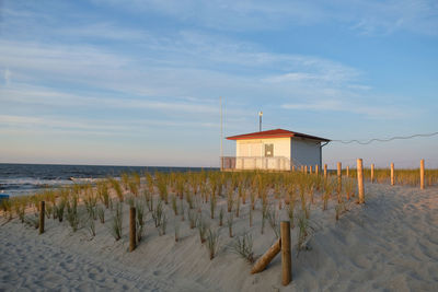 Hut on beach by sea against sky