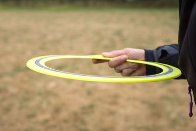 Midsection of person holding plastic disc on field