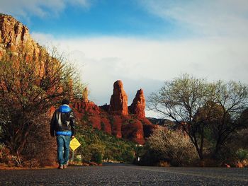 Rear view of woman standing against trees