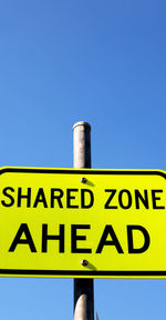 Low angle view of information sign against blue sky