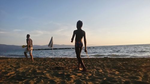 People on beach against sky during sunset