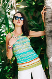 Beautiful woman standing by tree trunk