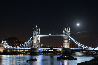 Illuminated london bridge over thames river at night with supermoon
