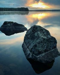 Rock formation in sea against sky during sunset