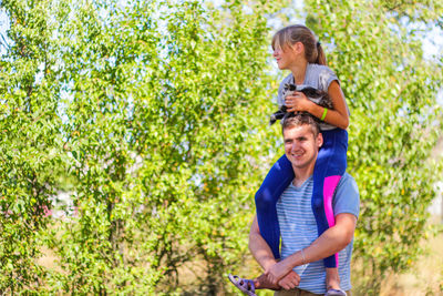 Brother riding sister on back. portrait of happy girl on man shoulders, piggyback. girl holding cat