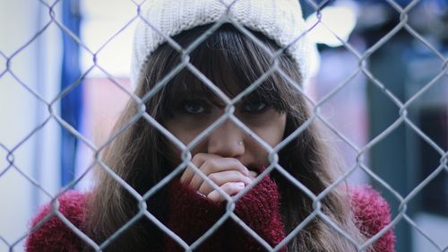 Close-up of young woman behind fence