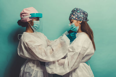 Doctors wearing protective suit embracing against wall