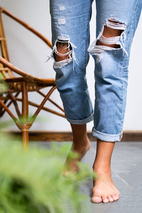 Bare feet woman wearing ripped jeans on terrace.