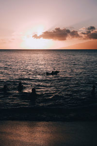 Silhouette people at beach against sky during sunset