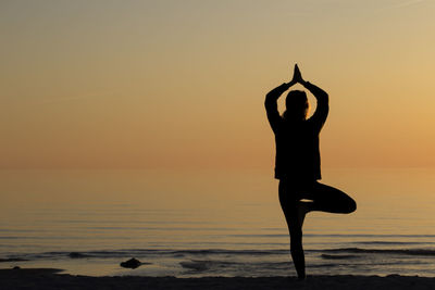 Silhouette man standing by sea against sky during sunset