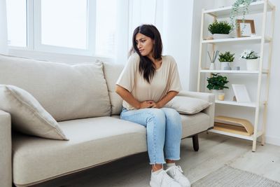 Portrait of young woman sitting on sofa at home