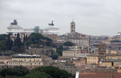 Buildings in city against cloudy sky