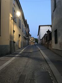 Empty road amidst buildings against sky in city