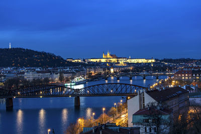 Bridges over vltava river in city against sky at night
