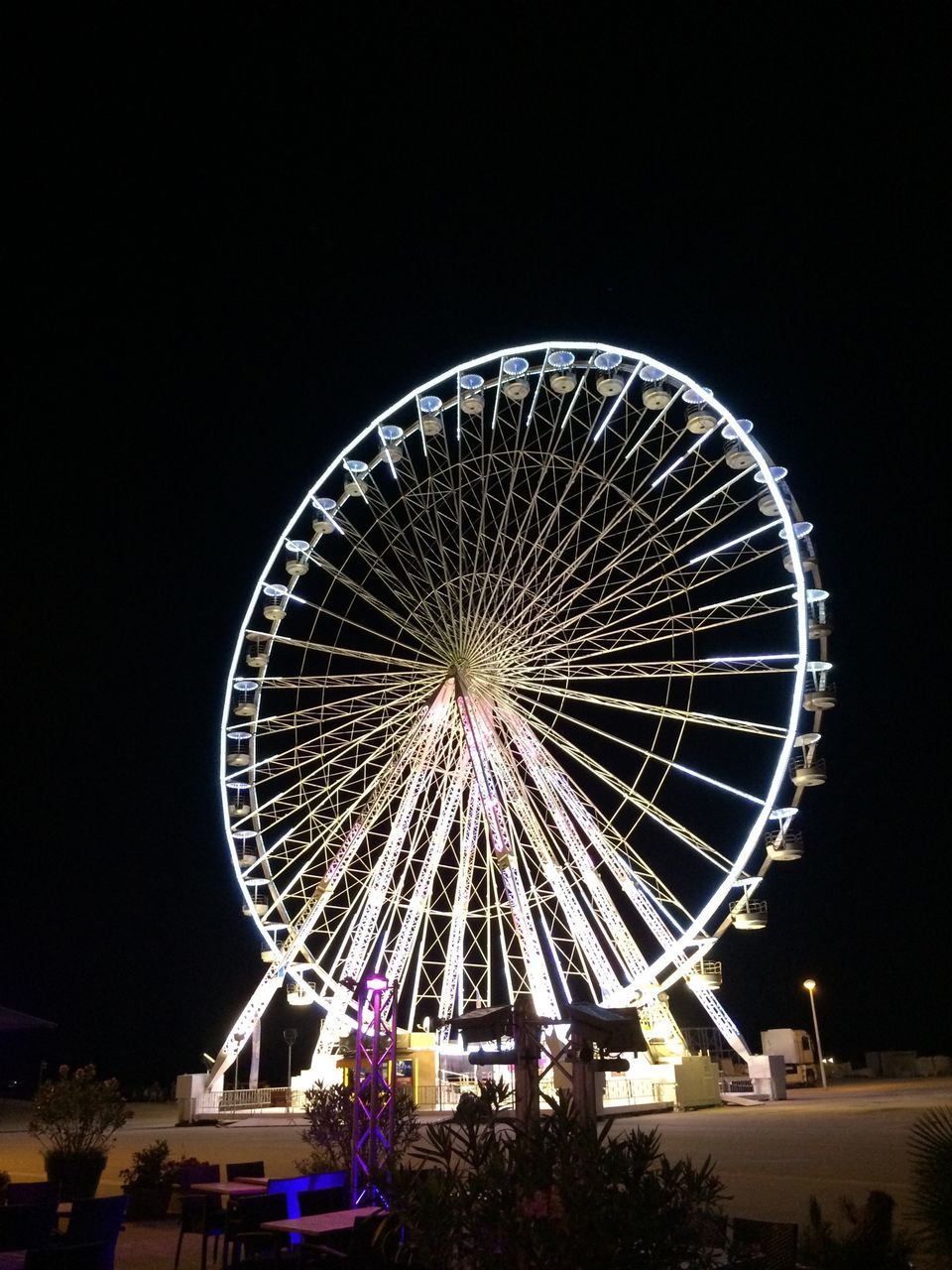 ferris wheel, amusement park ride, amusement park, illuminated, arts culture and entertainment, night, low angle view, sky, clear sky, copy space, built structure, glowing, outdoors, large, circle, no people, fun, architecture, lighting equipment, traveling carnival