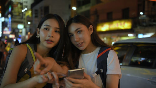 Portrait of young woman using smart phone in city at night