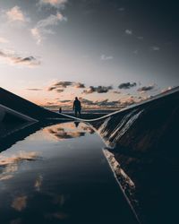 Silhouette person standing by railing against sky during sunset