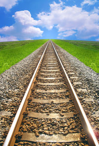 Surface level of railroad tracks on field against sky