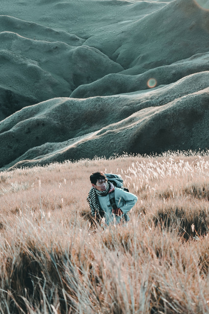 one person, leisure activity, mountain, beauty in nature, nature, scenics - nature, land, men, non-urban scene, real people, lifestyles, environment, adult, landscape, plant, young adult, field, full length, activity, outdoors