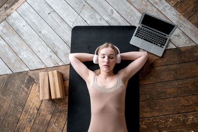 High angle view of woman using laptop on wooden floor