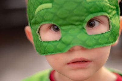 Close-up portrait of boy wearing green mask