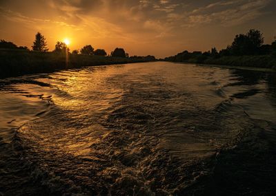 Scenic view of river against sky at sunset