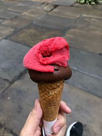 Low section of person holding ice cream on footpath
