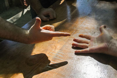 Cropped hands of friends playing rock paper scissors on table