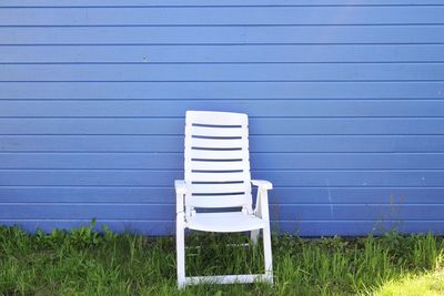 Empty chair on field against blue wall