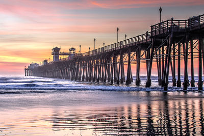 Pier over sea against sky during sunset