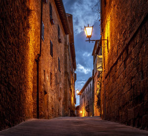 Street amidst buildings against sky at dusk