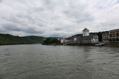 Buildings by river against sky in town