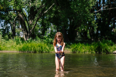 Portrait of woman standing by lake against trees